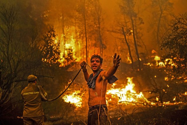 A resident holds an empty water hose on Evia (ANGELOS TZORTZINIS/AFP via Getty Images)
