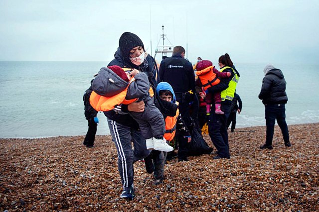 A migrant carries her children after being rescued while crossing the English Channel. Credit: BEN STANSALL/AFP via Getty Images