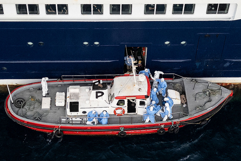 Health workers assist patients from the cruise ship MV Hondius. Credit: Getty